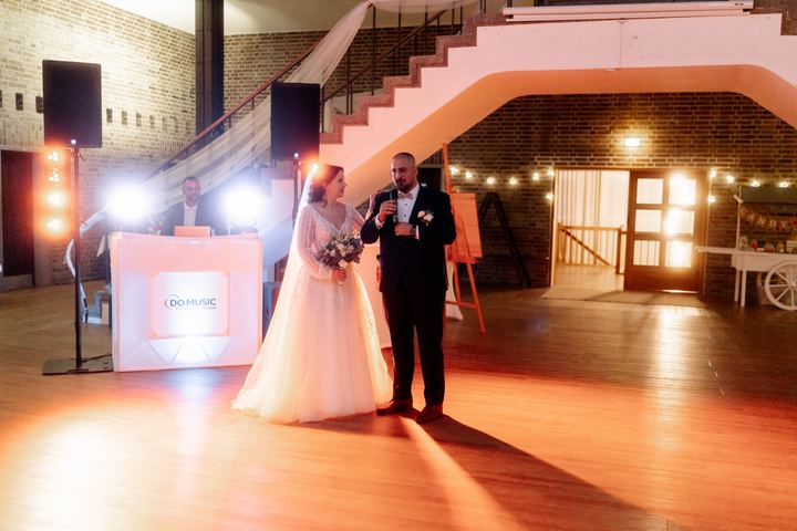 Braut und Bräutigam am DJ-Pult in warmem Licht bei einer Hochzeit