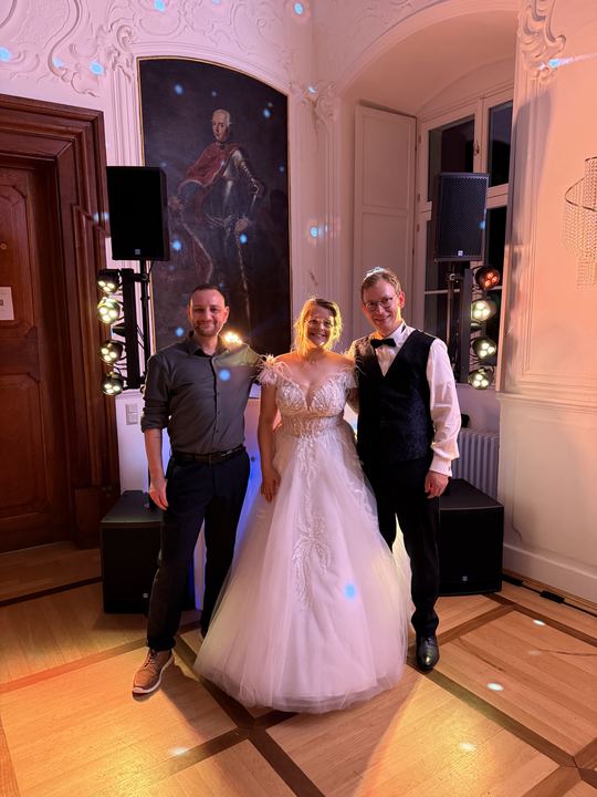 Festsaal mit Gemälde im Hintergrund, davor Brautpaar und DJ Marco Hilse